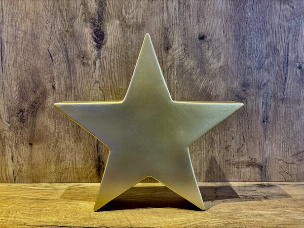 Product image: golden plastic star leaning against a sandstone wall